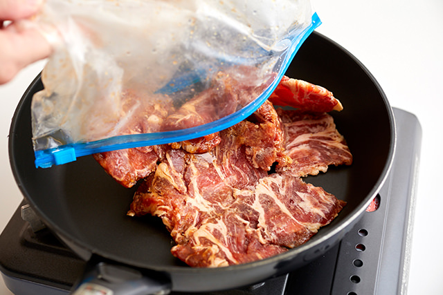 フライパンに凍った豚肉を入れている写真