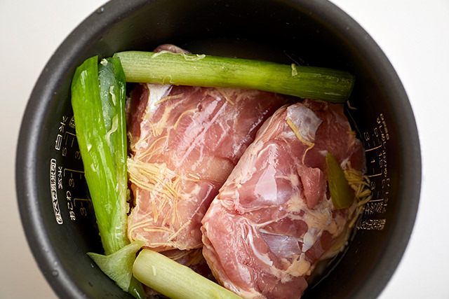 炊飯器に鶏もも肉、香味野菜を入れた写真