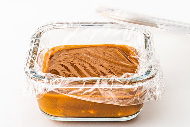 カレーが入ったガラス製密閉容器にラップをかけている写真