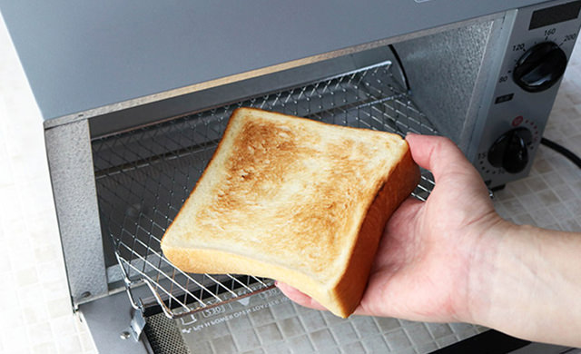 トースターから焼き上がった食パンを取り出す写真