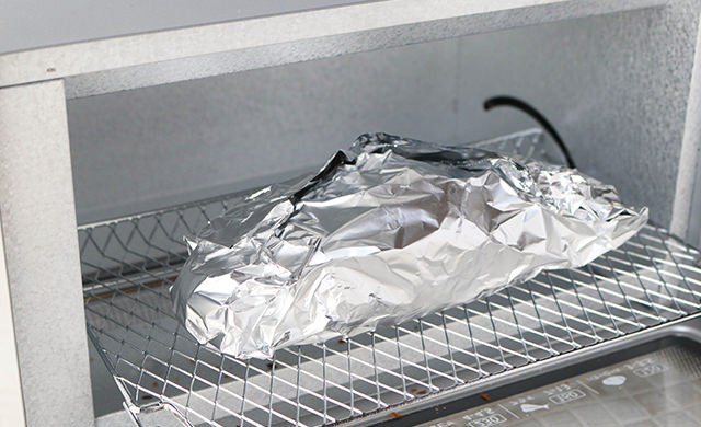 ホイルに包んだバゲットをトースターに入れた写真