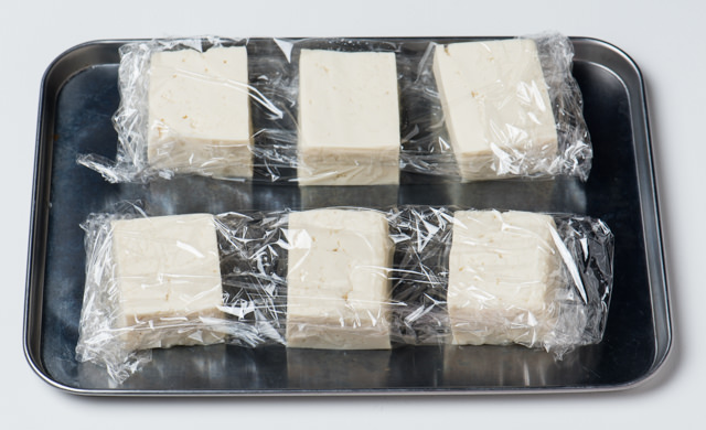 半丁ごとにラップに包んで並べた豆腐の写真