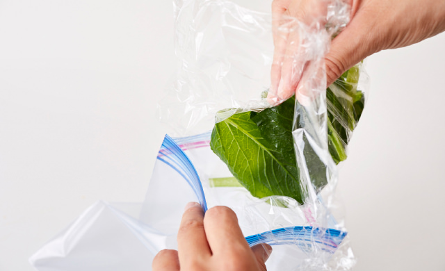 凍った小松菜を冷凍用保存袋に移している写真