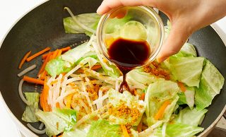 炒めた野菜に味付けをする写真