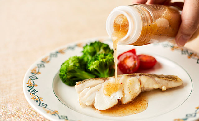 タラのソテーにドレッシングをかける写真