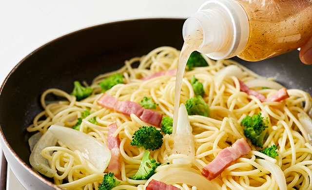 炒めているパスタにドレッシングを加える写真