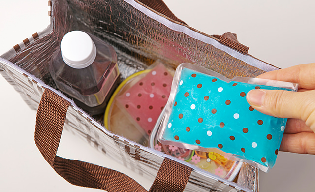 保冷バッグにそうめんそ入れた容器、トッピング具材を入れた容器、ペットボトルに入れて半冷凍にしためんつゆを入れたところに、保冷剤を入れようとしている写真