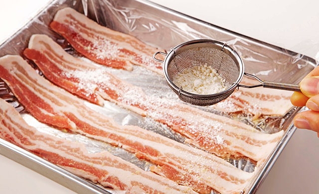 豚バラ薄切り肉に塩、こしょうした後、茶こしで小麦粉をふっている写真