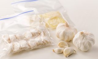 丸ごとと皮ごとバラバラにした生のにんにく、ラップで包んで冷凍用保存袋に入れた皮ごと冷凍にんにく、みじん切りにしてラップに包んで冷凍用保存袋に入れた冷凍にんにくの写真