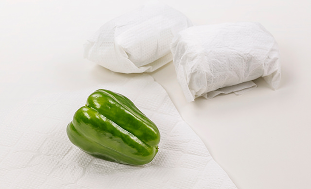 手前にキッチンペーパーにのったピーマン、背景にキッチンペーパーに包まれたピーマン2個