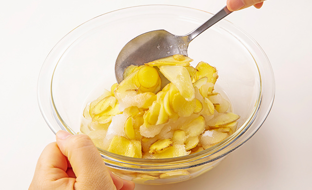 耐熱ボウルに入った生姜の薄切り、グラニュー糖、水を混ぜている写真