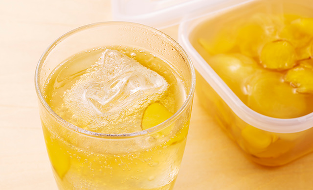 手前に氷を浮かべたグラスに入ったジンジャーエール、奥に保存容器に入ったジンジャーシロップの写真