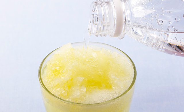 冷凍シロップを入れたグラスに炭酸水を注いでシャリシャリジンジャーエールを作っている写真