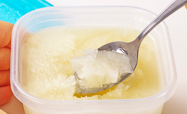 保存容器に冷凍保存したジンジャーシロップをスプーンですくっている写真