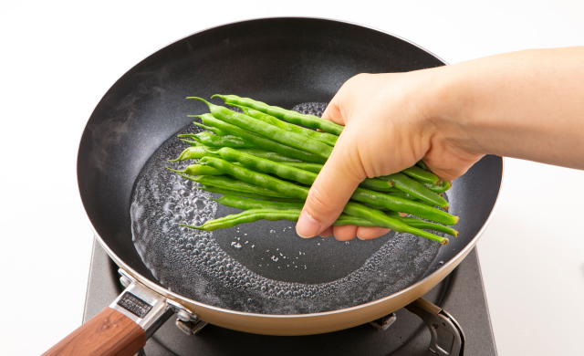 フライパンにいんげんを入れている写真