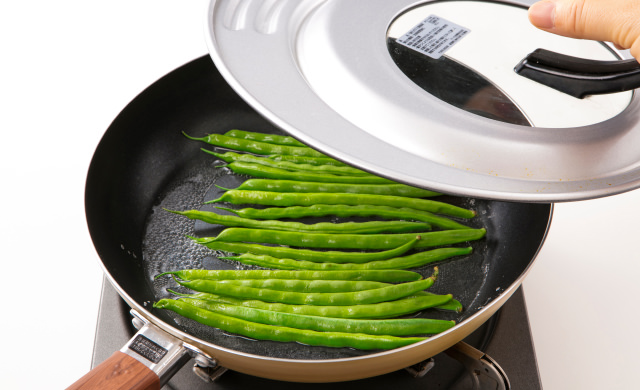 いんげんをゆでているフライパンにふたを閉めようとしている写真