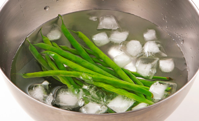 ゆで上げたいんげんを氷水に入れている写真