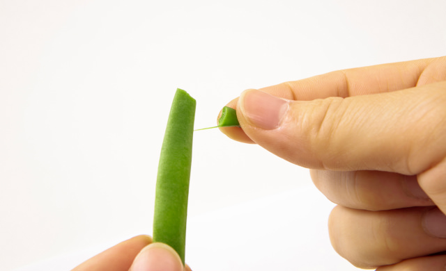 いんげんのヘタと筋を取っている写真