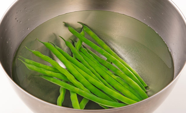 冷水に入れて粗熱をとっているいんげんの写真