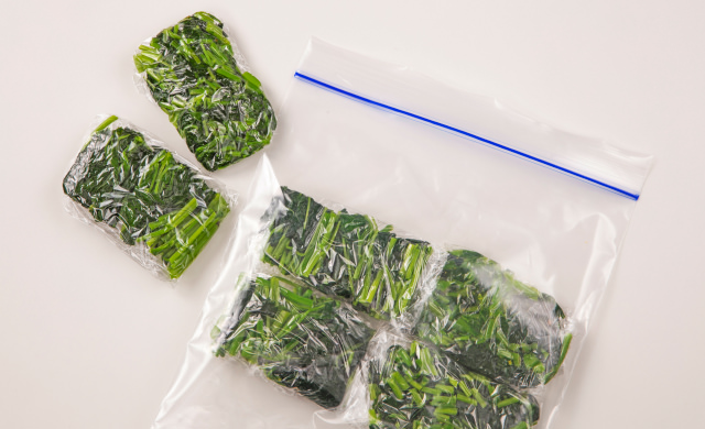 ゆでたモロヘイヤをざく切りや細かく刻んで小分けにし、ラップで包んだもの、それを冷凍用保存袋に入れた写真