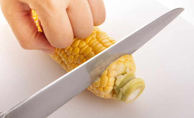 とうもろこしの端を切っている写真