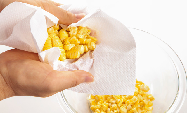 水気を拭き取りながらとうもろこしの実をほぐしている写真