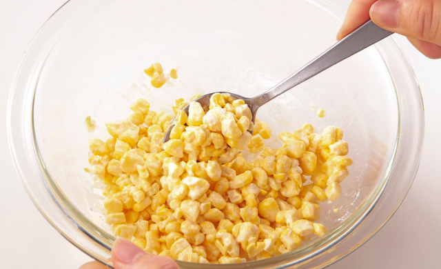 薄力粉と絡めたとうもろこしに塩と水を入れてよく混ぜ合わせている写真