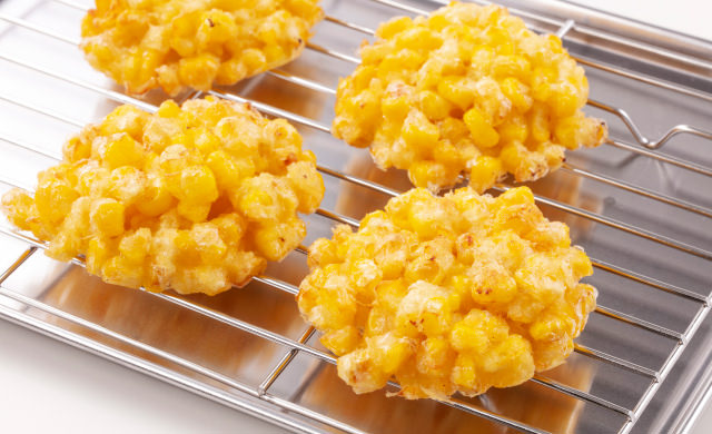 揚げ網に上げたとうもろこしの天ぷら4個の写真