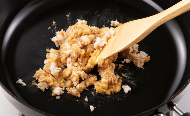 フライパンに味噌とほぐしたアジの身を入れて、木べらを使って弱火で炒っている写真