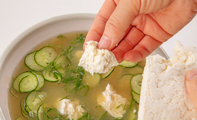 豆腐を指でちぎって冷や汁に入れている写真