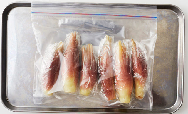 ラップで包んだみょうがを冷凍用保存袋に入れ、金属製バットにのせた写真