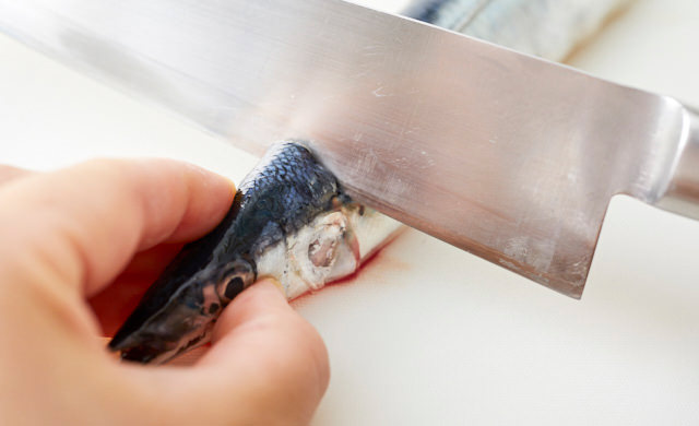 さんまの頭の部分に背骨を折るように包丁を入れている写真