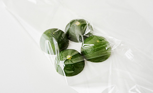 ラップの上に、横半分に切って切り口を下にして並べたすだちの写真