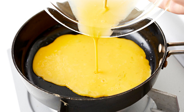 フライパンに卵液を入れて焼いている写真