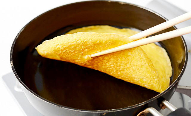 フライパンで焼いた卵を菜箸を使って取り出している写真