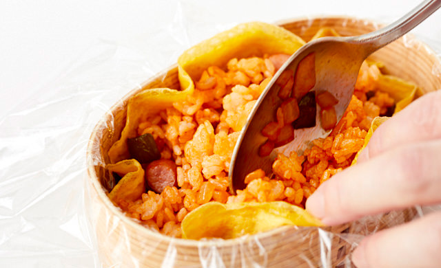 お弁当箱に入れた薄焼き卵のなかにケチャップライスを詰めている写真