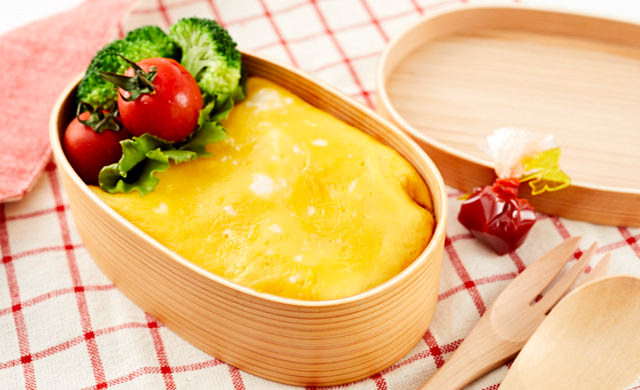 まげわっぱのお弁当箱に入っているオムライス、後ろにラップに包んだケチャップがある写真