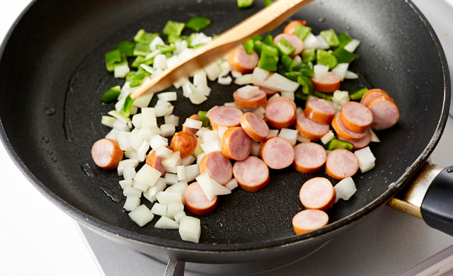 フライパンで玉ねぎ、ピーマン、ソーセージを炒めている写真