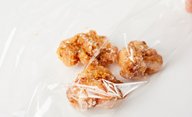 唐揚げを3個まとめてラップの上に置き、包もうとしている写真