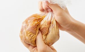 ポリ袋に入れた鶏もも肉をもんでいる写真