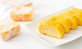 手前に食べやすく切った卵焼きを並べた皿盛り、後ろに食べやすく切ってラップで包んだ冷凍卵焼きが保存袋から出ている写真