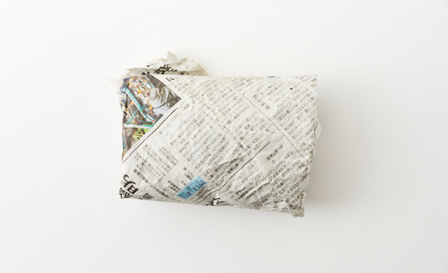 新聞紙に包まれた里芋の写真