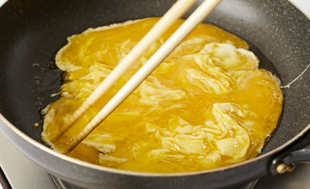 卵液を菜箸で混ぜている写真