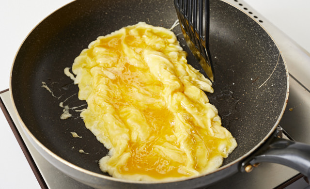フライ返しで卵を寄せている写真