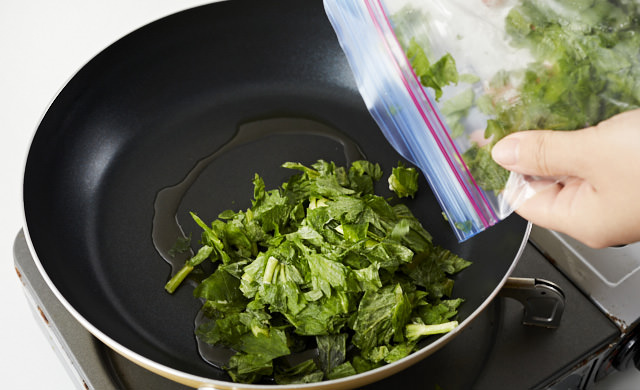 冷凍したセロリの葉をフライパンに入れている写真