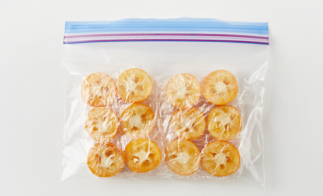 ラップで包んだきんかんを冷凍用保存袋に入れている写真