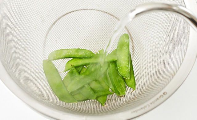 冷凍した絹さやに熱湯をかけている写真