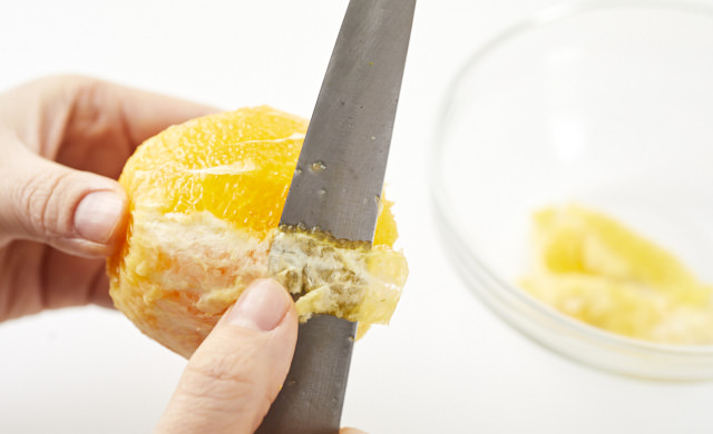 オレンジの薄皮をむいている写真