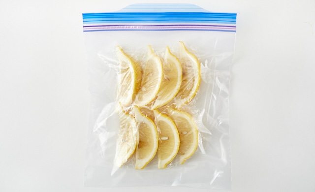 ラップで包んだくし形切りのレモンが冷凍用保存袋に入っている写真