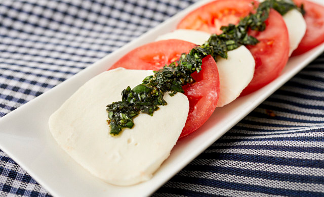 バジルのオリーブオイル漬けをのせたカプレーゼの写真